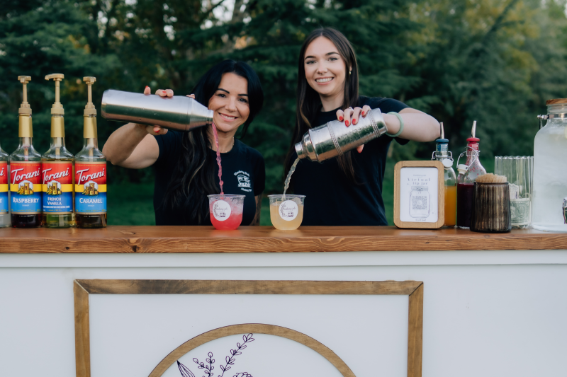 Amber and Katelynn pouring drinks behind the bar.